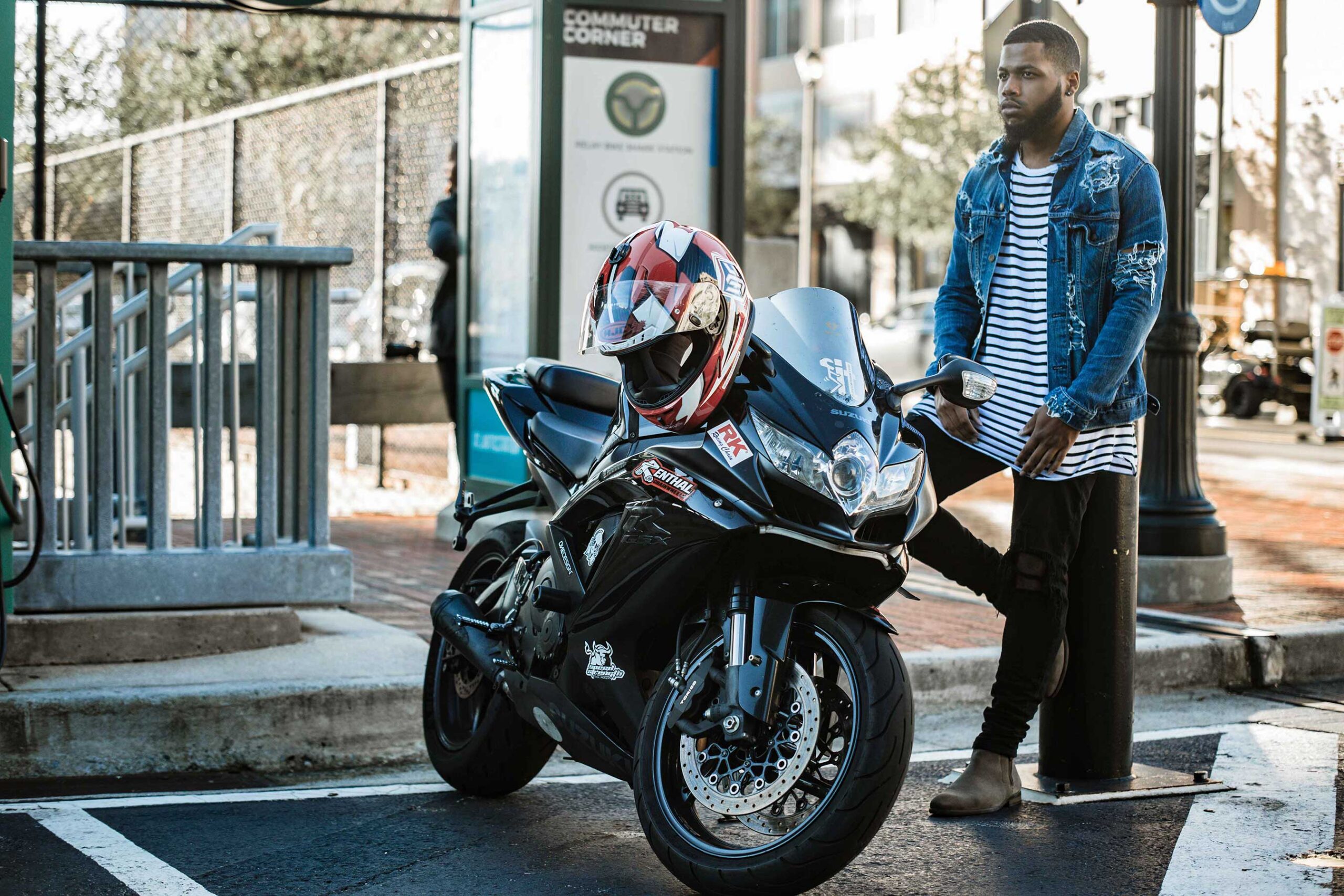 Editorial photo of a young African American man standing next to a motorcycle